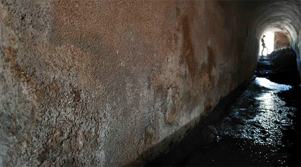 dark tunnel with water and silhouetted figure